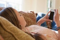 Teenager-Mädchen liegt mit Kopfhörern auf Sofa — Stockfoto
