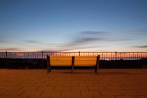 Скамейка за перилами с облачным вечерним небом — стоковое фото