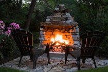Two chairs in front of outdoor fireplace — Stock Photo