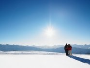 Casal andando na neve no topo da montanha — Fotografia de Stock