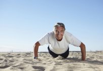 Senior homme faire des pompes sur la plage — Photo de stock