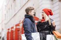Young shopping couple and red phone boxes, London, UK — Stock Photo