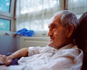 Elderly man sitting in armchair — Stock Photo
