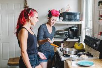 Duas jovens mulheres preparando comida em placa de cozinha — Fotografia de Stock
