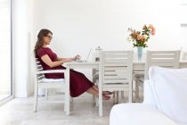 Junge Frau sitzt am Tisch und benutzt Laptop — Stockfoto