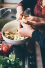 Immagine ritagliata di uomo e donna affettare carciofi globo in cucina — Foto stock