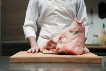 Butcher with head of pig — Stock Photo