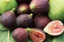 Whole and halved figs pile with leaves — Stock Photo