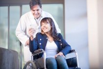 Femme en fauteuil roulant assistée par un infirmier — Photo de stock