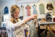 Молода жінка дивиться верхній одяг в магазині — стокове фото