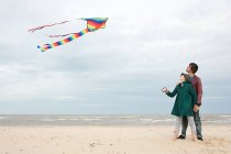 Casal jovem com papagaio junto ao mar — Fotografia de Stock