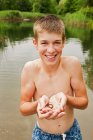 Хлопчик-підліток тримає маленьку рептилію в руках біля озера — стокове фото
