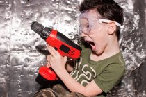 Niño con herramienta eléctrica y gafas de seguridad - foto de stock