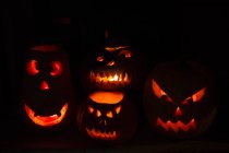 Beleuchtete Kürbis Jack o 'Laternen auf schwarzem Hintergrund, Feiern zu Halloween — Stockfoto