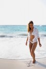 Junge Frau im weißen Bikini am Strand — Stockfoto