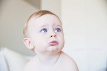 Portrait of blue eyed dribbling baby boy looking up from bed — Stock Photo