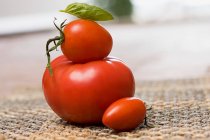 Pila de tomates maduros con hoja de albahaca - foto de stock
