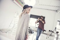 Мужчина фотограф фотографирует женскую модель на белом фоне студии — стоковое фото