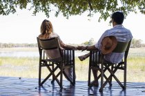 Couple romantique tenant la main tout en étant assis au safari lodge — Photo de stock