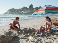 Garçon et fille faisant des châteaux de sable sur la plage — Photo de stock