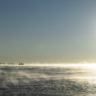 Seascape com barco de pesca no horizonte na névoa do sol da alvorada — Fotografia de Stock