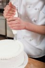 Chef donna glassa una torta, primo piano vista parziale — Foto stock