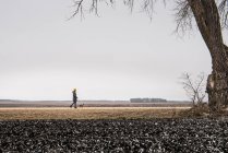 Woman walking dog on rural landscape — Stock Photo