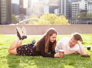 Parejas jóvenes tomando un café en la hierba, Melbourne, Victoria, Australia - foto de stock