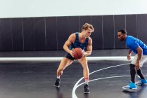 Dos jugadores de baloncesto practican defensa de pelota en cancha de baloncesto - foto de stock