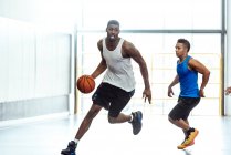 Jogadores de basquete masculino correndo com bola e defendendo na quadra de basquete — Fotografia de Stock