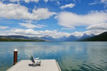 Liegestuhl am Steg mit malerischem Blick auf See und Bergkette — Stockfoto
