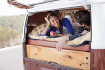 Пара лежить разом у задній частині кемперського фургона, посміхаючись — стокове фото