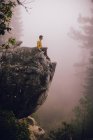 Молодой человек, сидящий на скале, глядя на вид, рядом с озером Шейвер, Калифорния, США — стоковое фото