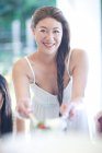 Porträt einer jungen Frau, die Freunden Essen serviert — Stockfoto