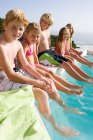 Kids sitting on edge of swimming pool — Stock Photo