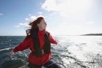 Young woman sailing with arms out — Stock Photo