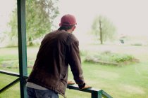 Мужчина стоит на веранде и смотрит на сад — стоковое фото