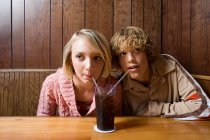 Couple d'adolescents partageant une boisson gazeuse — Photo de stock