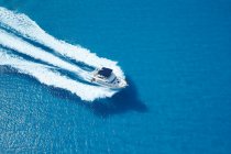 Motor yacht ploughing across blue sea water — Stock Photo