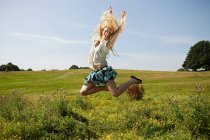 Молода жінка в полі, стрибає в повітрі — стокове фото