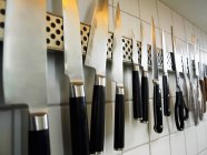 Ряд ножей и ножниц на кухонной стене — стоковое фото
