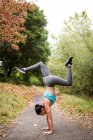 Mid adult woman training, doing handstand in park — Stock Photo