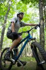 Людина в лісі з гірським велосипедом — стокове фото