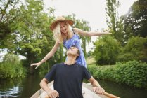 Young woman with boyfriend standing in rowing boat on river — Stock Photo