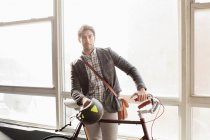 Uomo in piedi con bicicletta dal finestrino — Foto stock