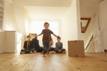 Retrato de un niño y una familia sentados en el suelo en un nuevo hogar - foto de stock