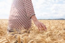 Mid section of woman in wheat field — Stock Photo