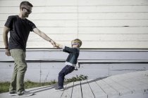 Мальчик вытаскивает отца на деревянный пандус — стоковое фото