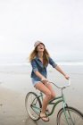 Woman riding bicycle on beach — Stock Photo