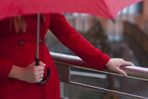 Imagem cortada de jovem mulher em guarda-chuva de transporte vermelho — Fotografia de Stock
